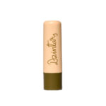 Dzintars Tūja Gentle Lip Balm stick – peach tube with olive green base and Dzintars script logo, white background