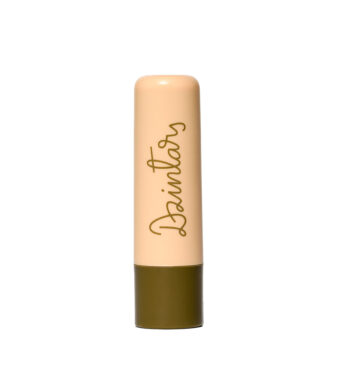 Dzintars Tūja Gentle Lip Balm stick – peach tube with olive green base and Dzintars script logo, white background