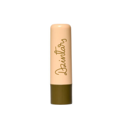 Dzintars Tūja Gentle Lip Balm stick – peach tube with olive green base and Dzintars script logo, white background