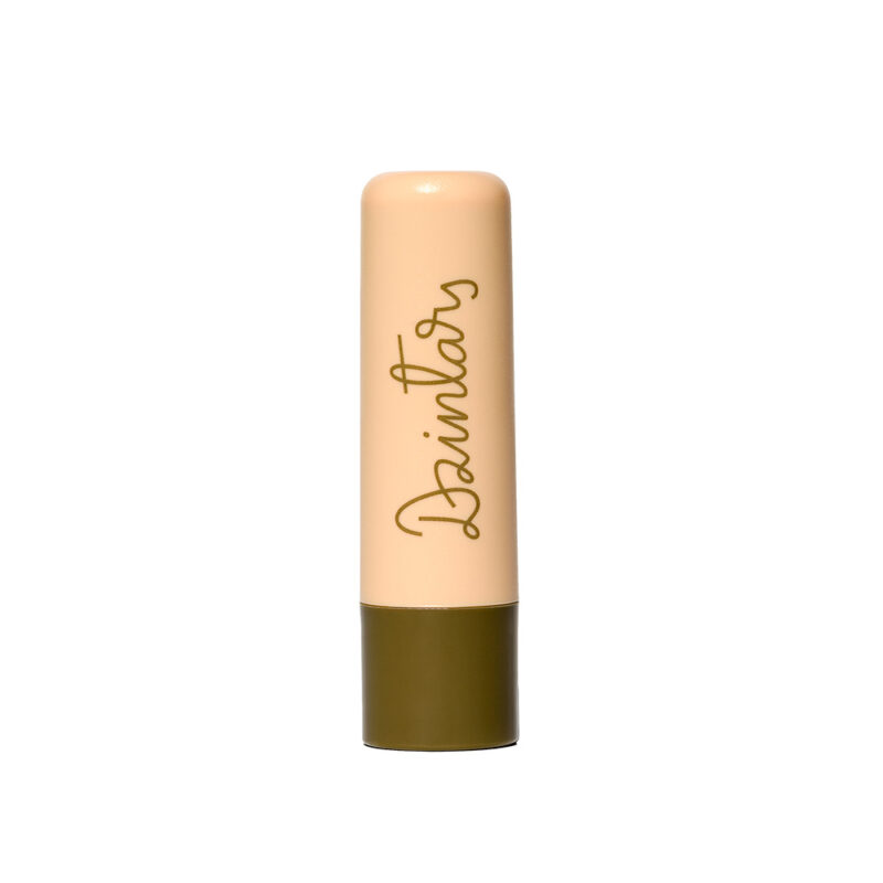 Dzintars Tūja Gentle Lip Balm stick – peach tube with olive green base and Dzintars script logo, white background