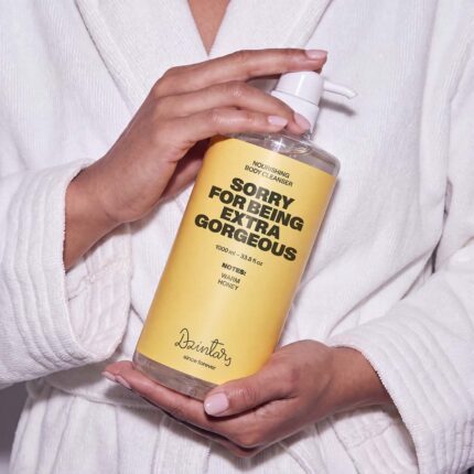 Person in white bathrobe holding Dzintars Sorry For Being Extra Gorgeous nourishing body cleanser 1000ml pump bottle